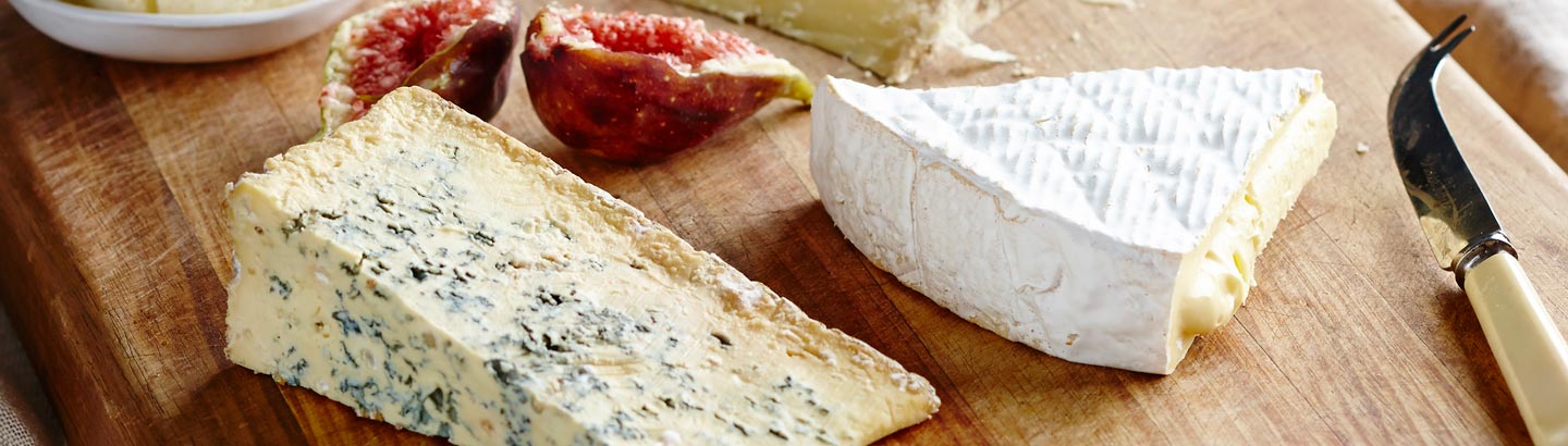 A picture of a selection of different kinds of cheese on a cheese platter. 