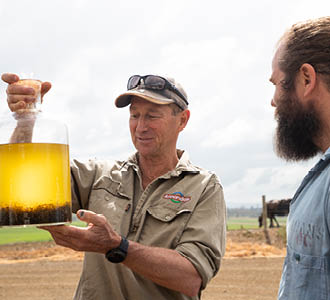 Dairy farmer looking at asparagopsis in jar thumbnail